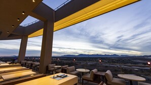 Un bar situé sur le toit, avec une terrasse, offrant une vue sur le paysage désertique et les montagnes à l’horizon.