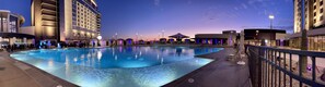 Una piscina con un deck perimetral, un jardín de cactus y un edificio moderno con balcones.