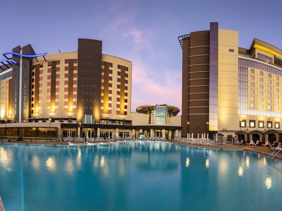 Un hotel con una piscina grande, varios balcones y un diseño arquitectónico moderno.