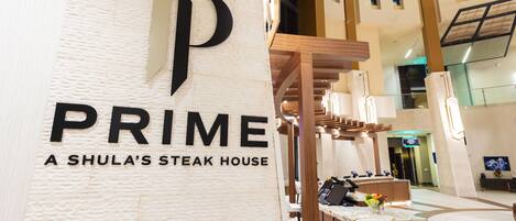 A reception area with a marble counter, a large 'P' logo, and a sign reading 'PRIME A SHULA'S STEAK HOUSE'.