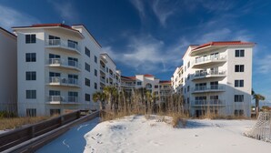 A beachfront hotel with multiple balconies, a sandy beach in front, and a clear blue sky. - Palm Beach Resort Orange Beach a Ramada by Wyndham (Orange Beach)