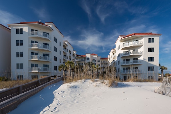 A beachfront hotel with multiple balconies, a sandy beach in front, and a clear blue sky. - Palm Beach Resort Orange Beach a Ramada by Wyndham (Orange Beach)