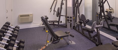 A gym with various exercise equipment, including dumbbells, a bench press, and a cable machine.