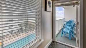 A balcony with blue chairs and a view of a pool. - Palm Beach Resort Orange Beach a Ramada by Wyndham (Orange Beach)