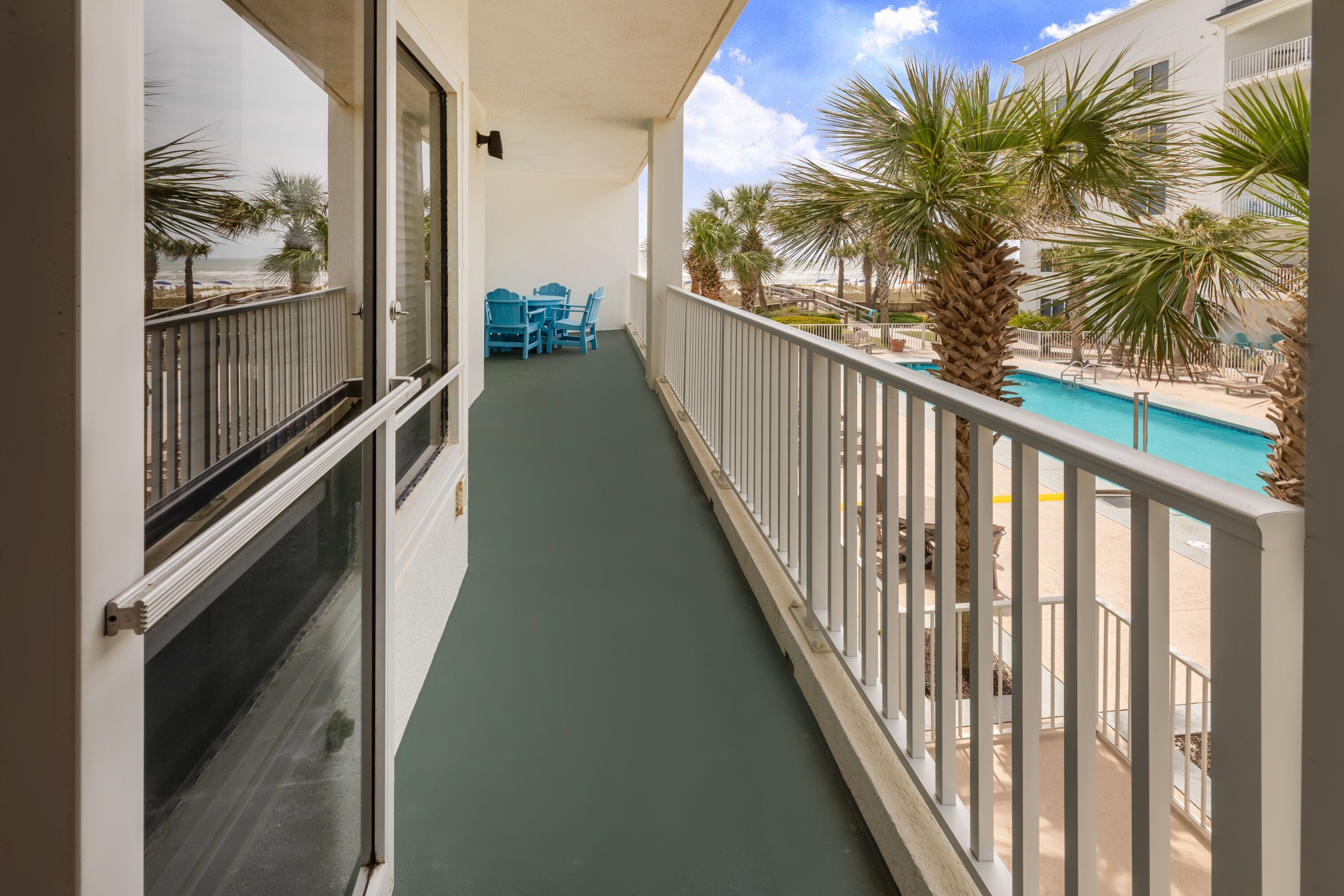 Un balcon avec vue sur une piscine et des palmiers.