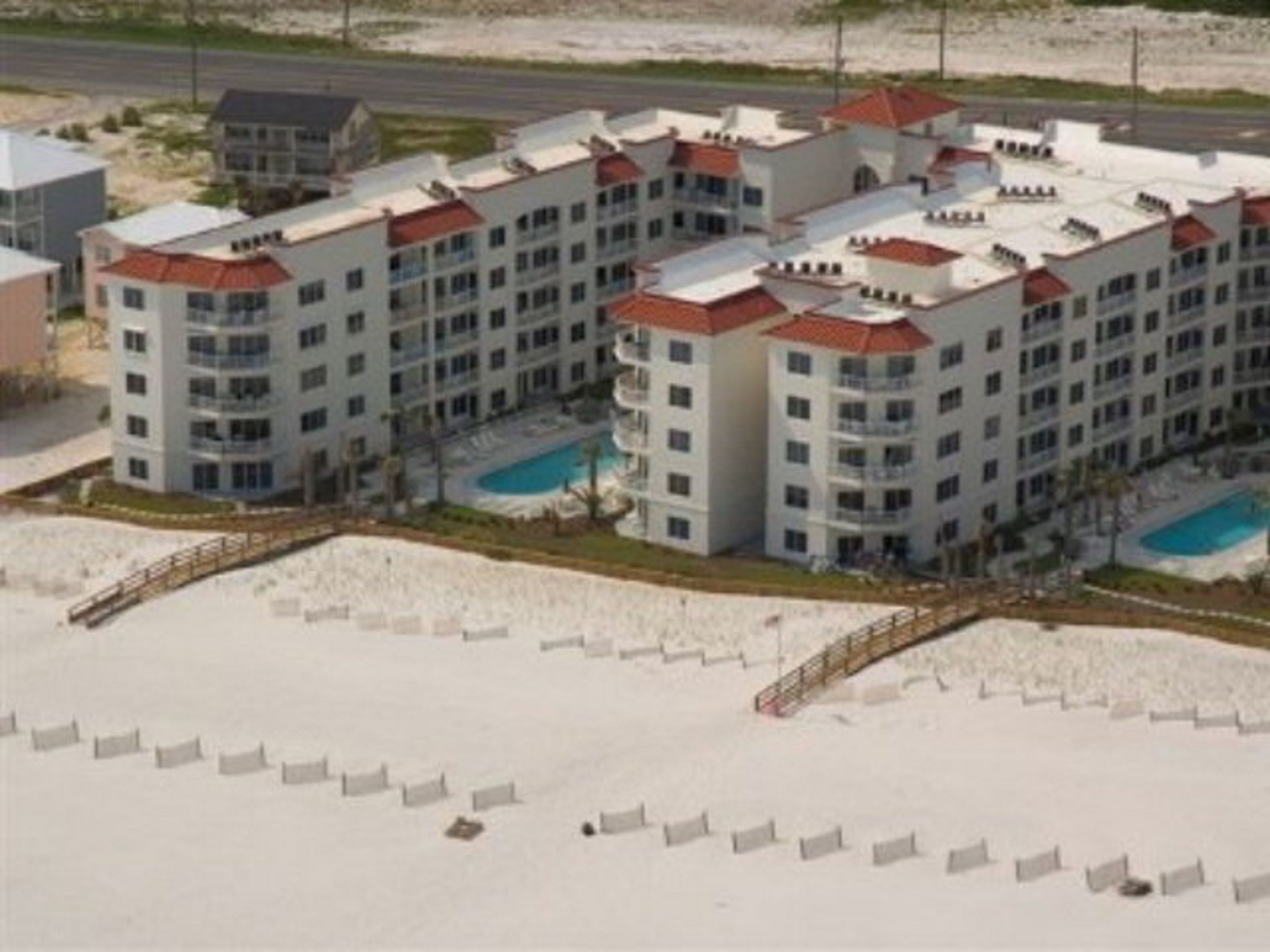 A multi-story hotel with a central courtyard, balconies, and a swimming pool.