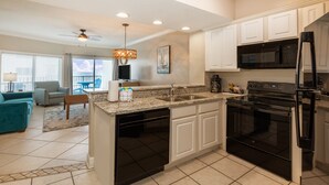 A modern kitchen with white cabinets, a black refrigerator, and a built-in oven. - Palm Beach Resort Orange Beach a Ramada by Wyndham (Orange Beach)