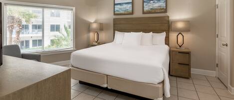 A bedroom with a bed, bedside tables, a desk, and a ceiling fan.