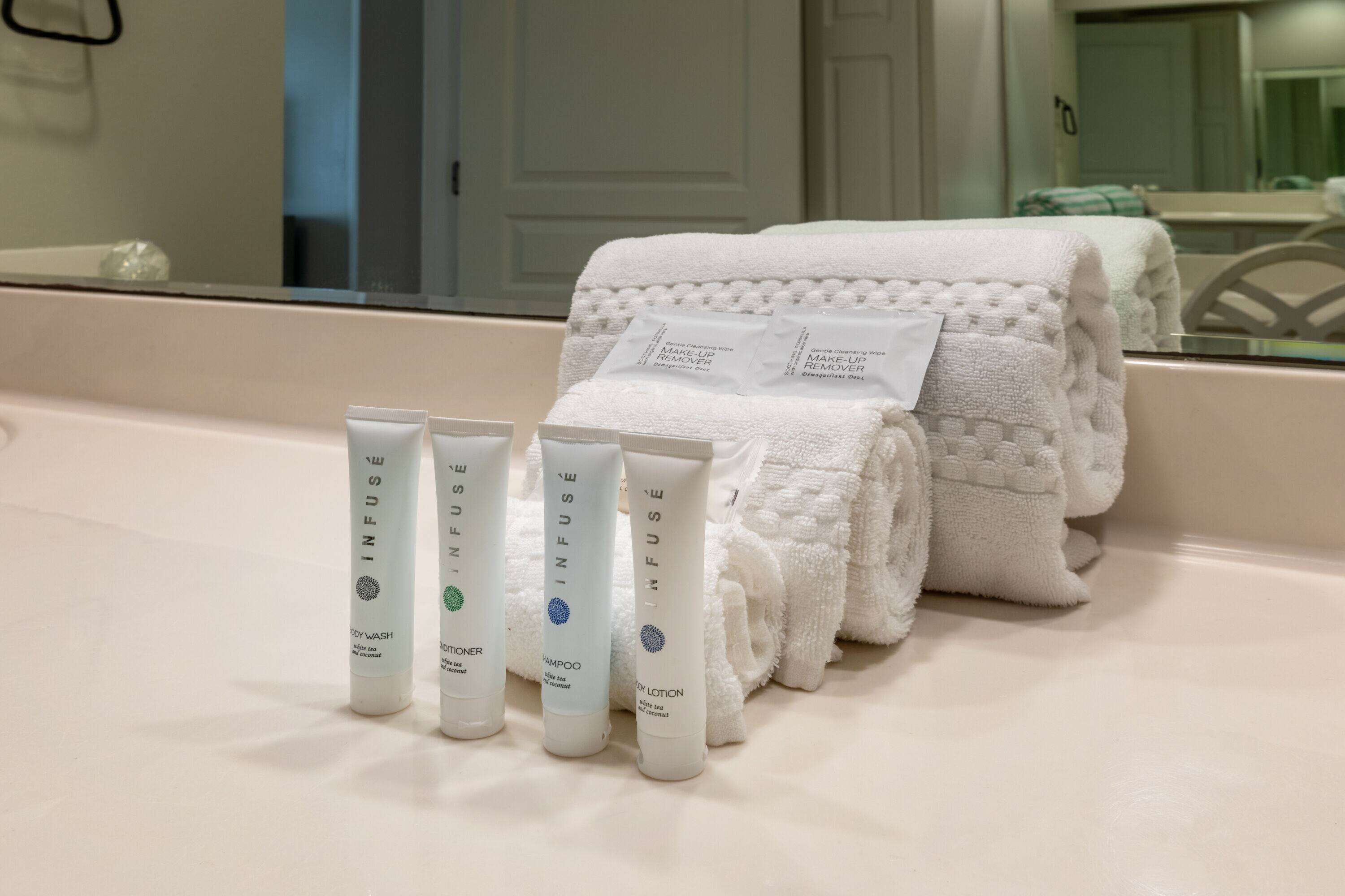 Ein Badezimmer mit einem weißen Waschbecken, einem Spiegel und Pflegeprodukten wie Duschgel, Shampoo und Lotion.