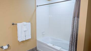 A bathroom with a bathtub, a towel rack with towels, a toilet paper holder, and a shower curtain.