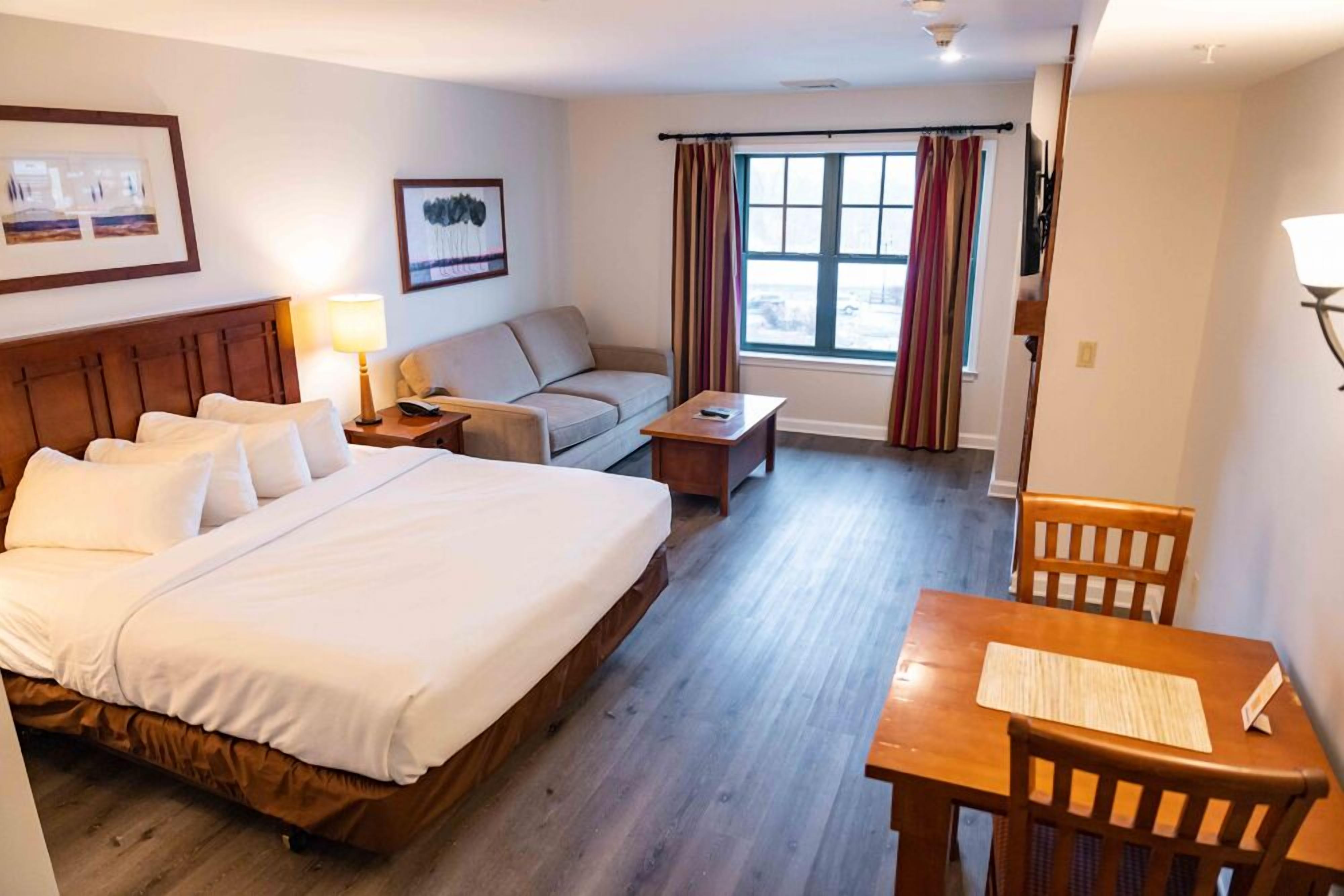 Una habitación de hotel con una cama grande, un sofá, una mesita y un escritorio con sillas.