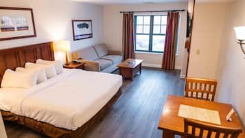 Una habitación de hotel con una cama grande, un sofá, una mesita y un escritorio con sillas.