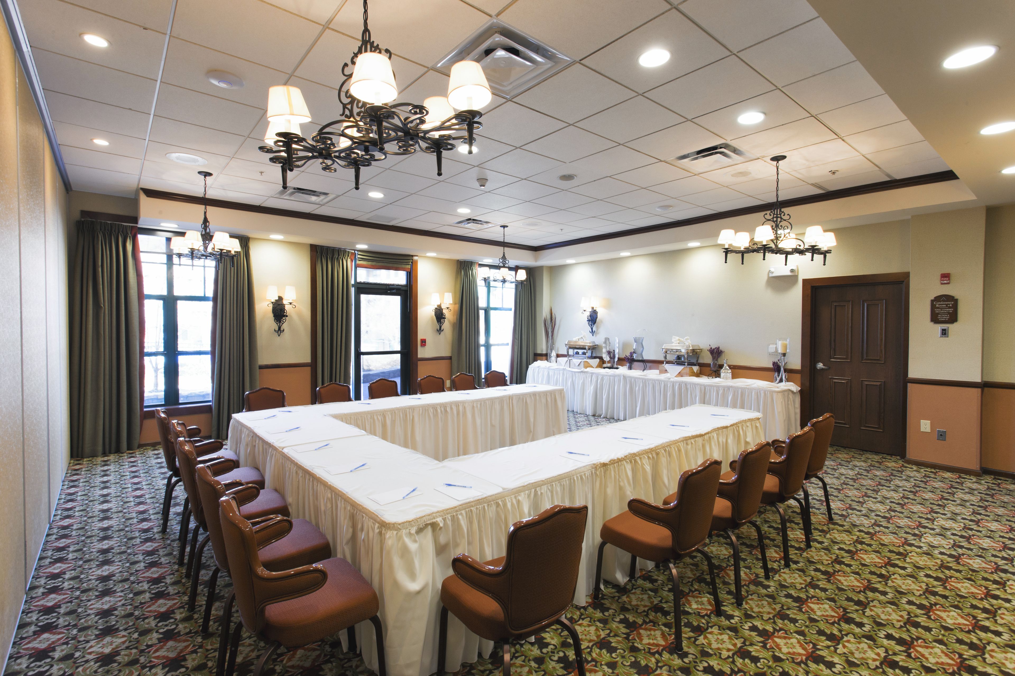 Une salle de conférence avec une longue table, des chaises, des lustres et une moquette à motifs.