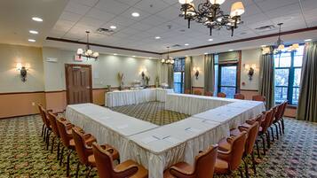 Un salón de conferencias con una mesa grande, sillas y una araña.