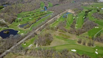 Vue aérienne d’un parcours de golf comportant plusieurs trous, des plans d’eau et des zones boisées environnantes.