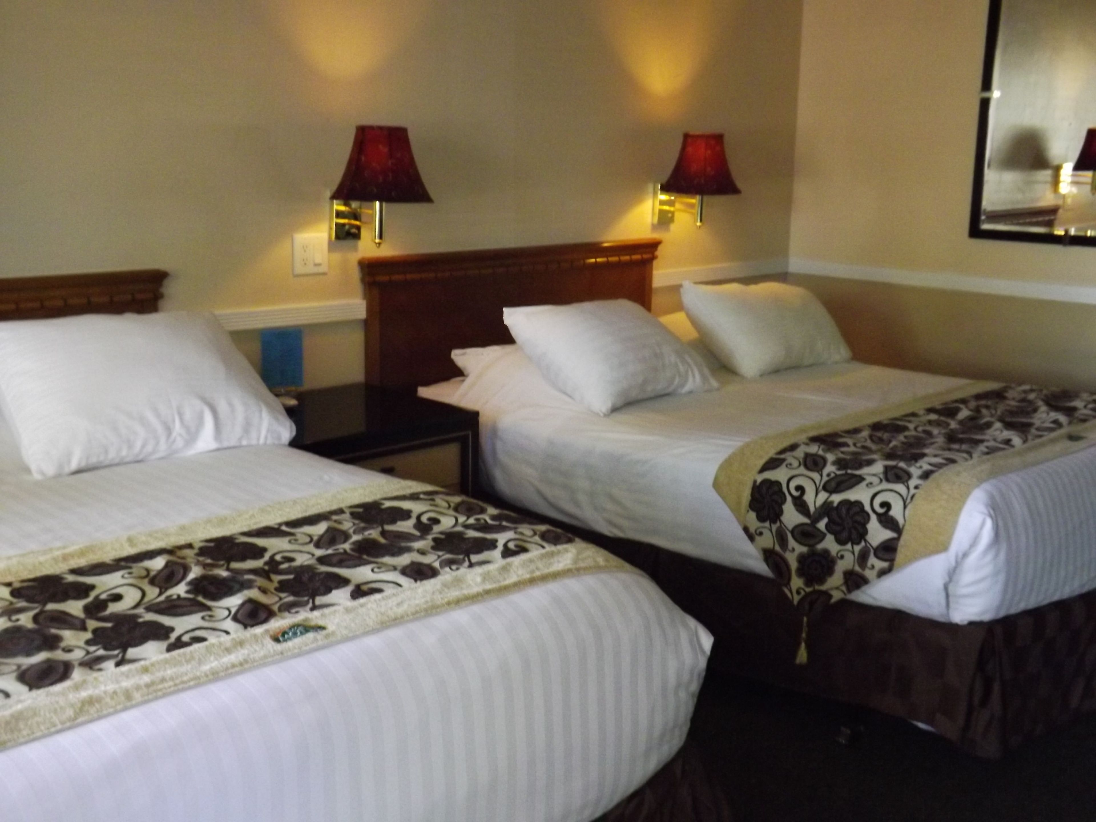Two single beds with headboards, a nightstand, and two wall-mounted lamps.