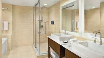 A modern bathroom with two sinks, a large mirror, and a glass-enclosed shower.