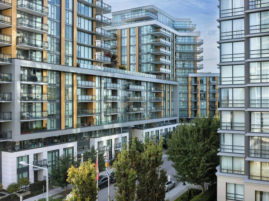 A modern multi-story residential building with balconies, large windows, and a clean architectural design.