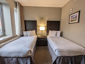 A hotel room with two single beds, a nightstand with a lamp, a telephone, and a framed picture on the wall. - King Edward Hotel  (Banff)