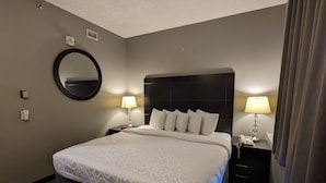 A hotel room with a large bed, two bedside tables with lamps, a round mirror, and a dark headboard. - King Edward Hotel  (Banff)