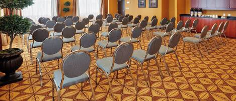 Un salón de conferencias con filas de sillas, un mostrador de recepción y una alfombra estampada.