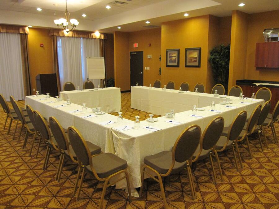 A conference room with long tables, chairs, a whiteboard, and a podium.