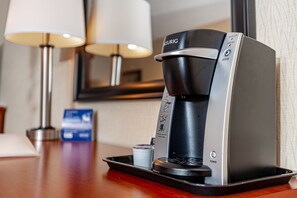 Una cafetera de hotel con portavasos, botón de encendido y botón de 'Preparar'.
