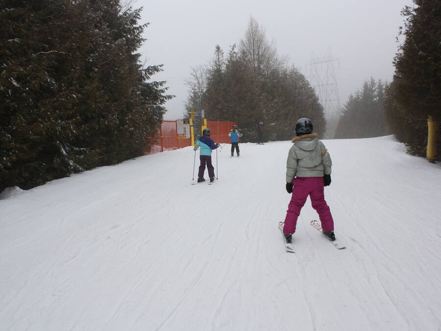 Una pista de esquí nevada con árboles y una valla.