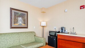 A hotel room with a sofa, a table, a kitchenette with a microwave, a coffee maker, and a sink. - Holiday Inn Express Hotel & Suites CLARINGTON - BOWMANVILLE by IHG (Clarington)