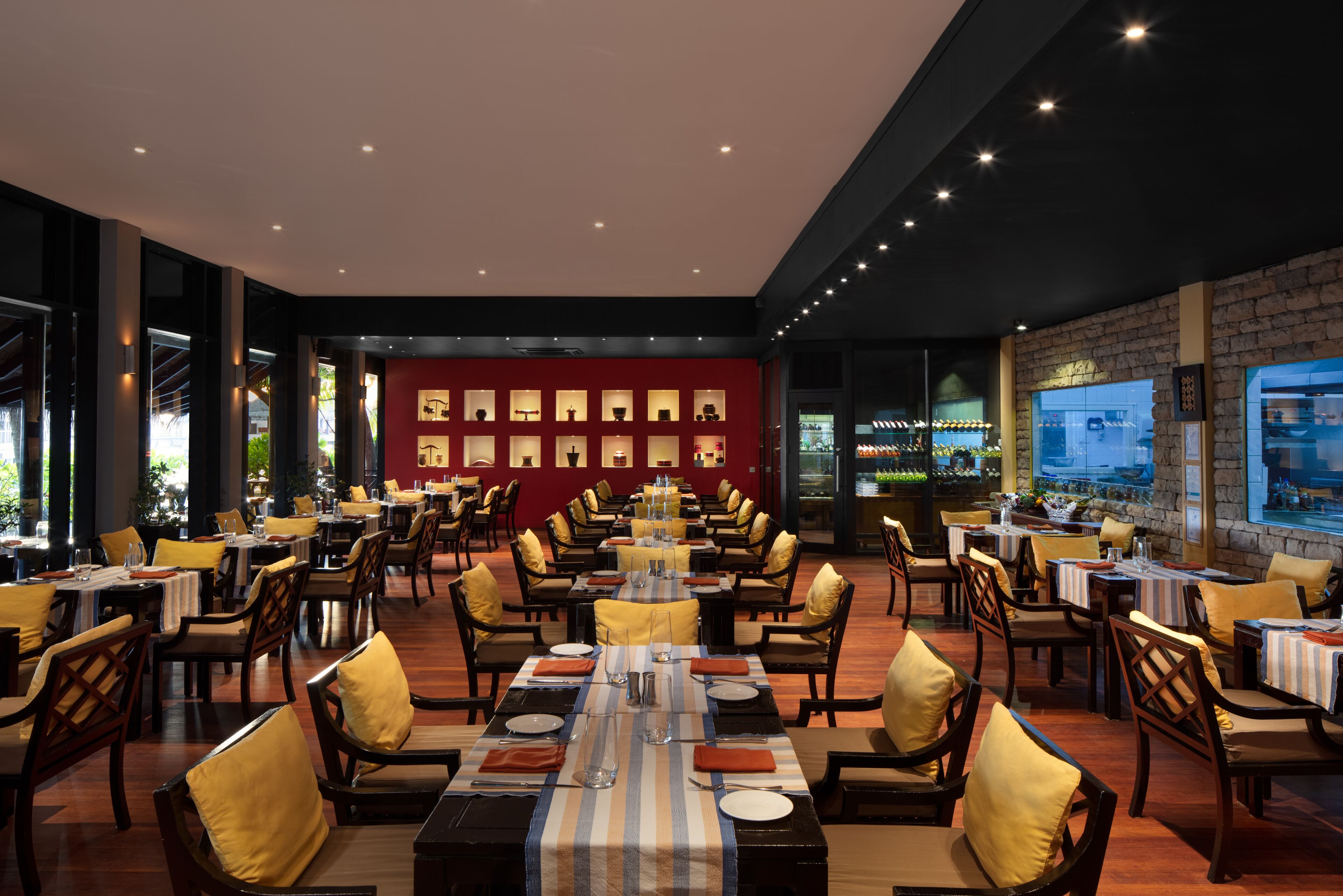 Een ruim restaurant met hoge plafonds, meerdere eettafels en stoelen.