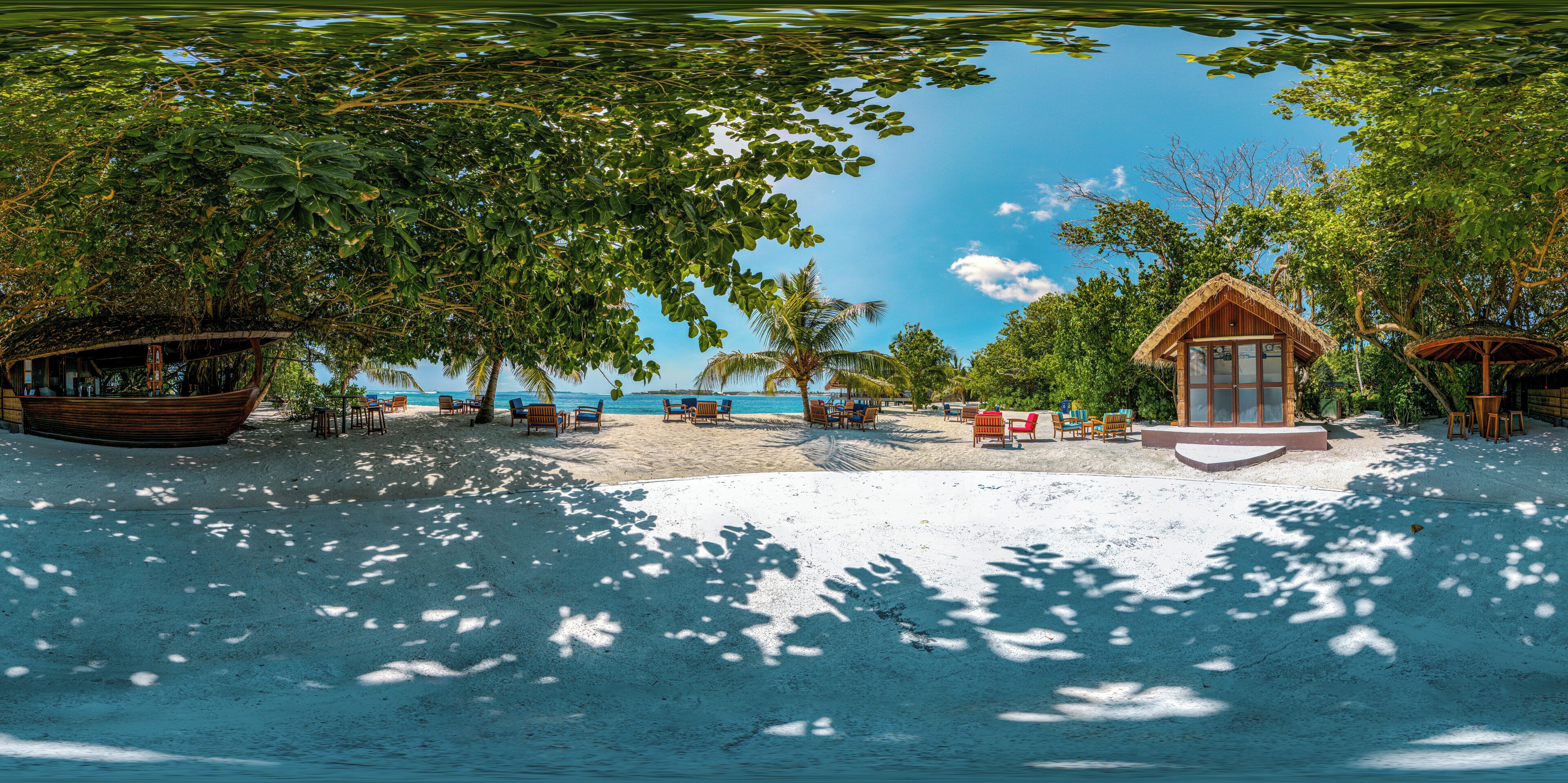 A beach with a wooden boat, lounge chairs, and a small building with a thatched roof.