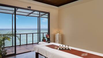 Relax in this serene spa room with a balcony overlooking the water, featuring a comfortable bed and a tranquil atmosphere.
