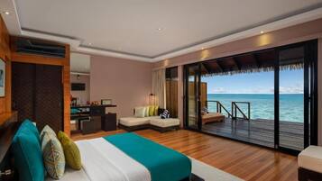 Un dormitorio con una cama grande, un escritorio, un sofá y un balcón con vistas al mar.