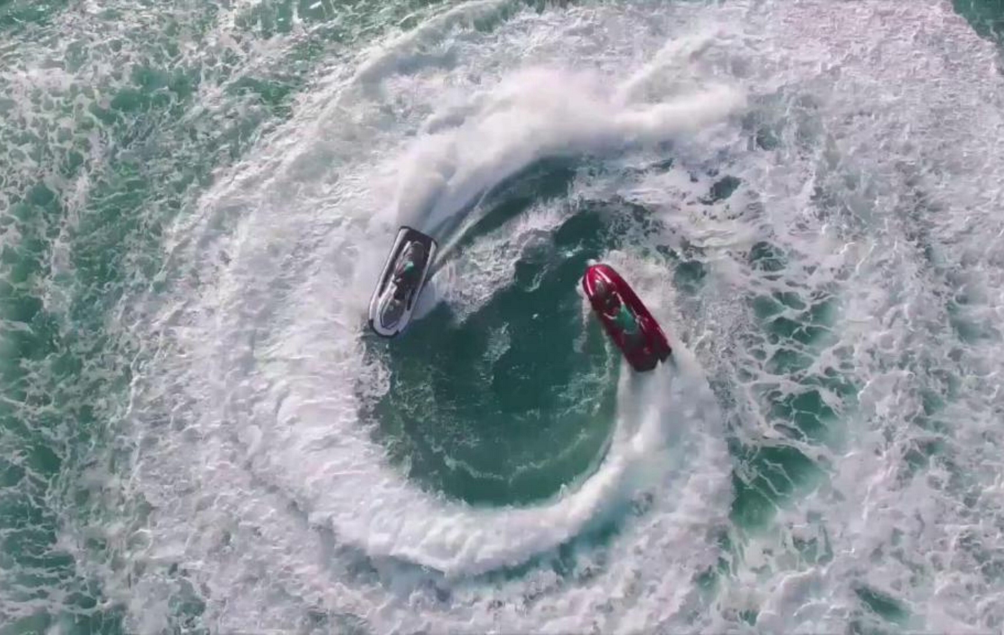 Two boats in a circular wave pattern in the ocean.