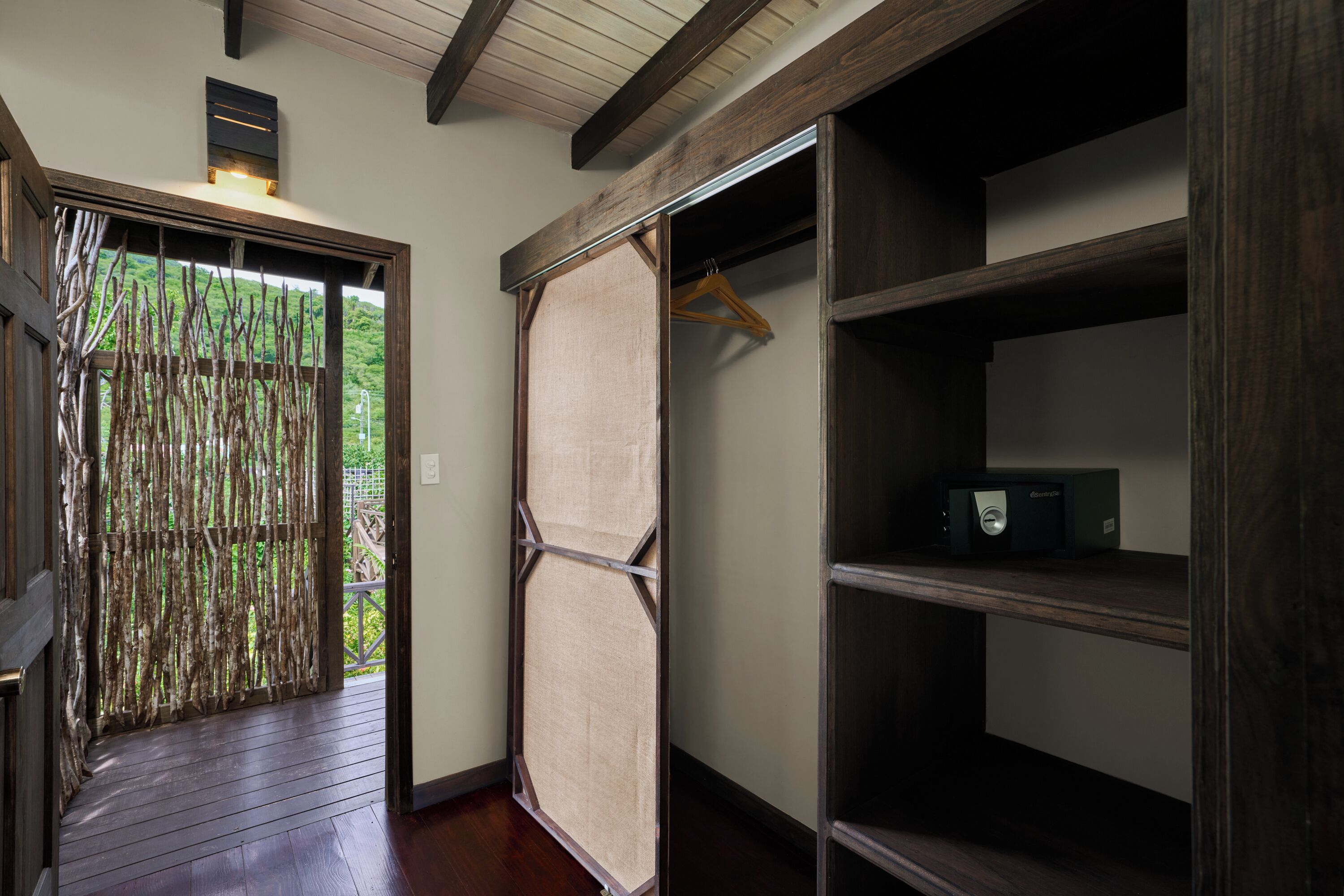 A room with a wooden floor, a wardrobe with multiple shelves, and a door with a bamboo screen.