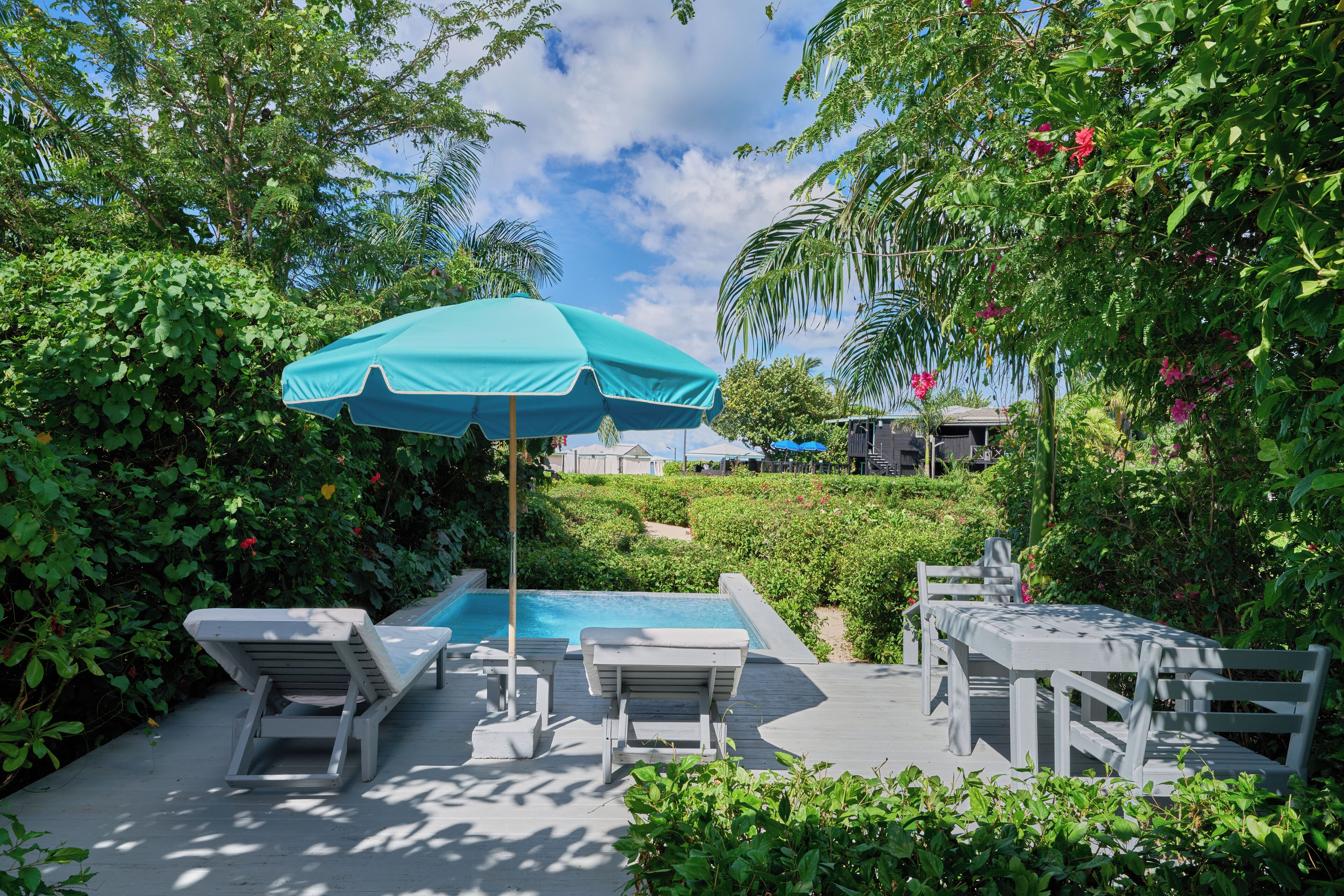 A poolside area with lounge chairs, a table, and an umbrella.