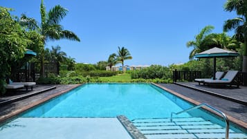 Alberca al aire libre, sombrillas en la alberca y camastros