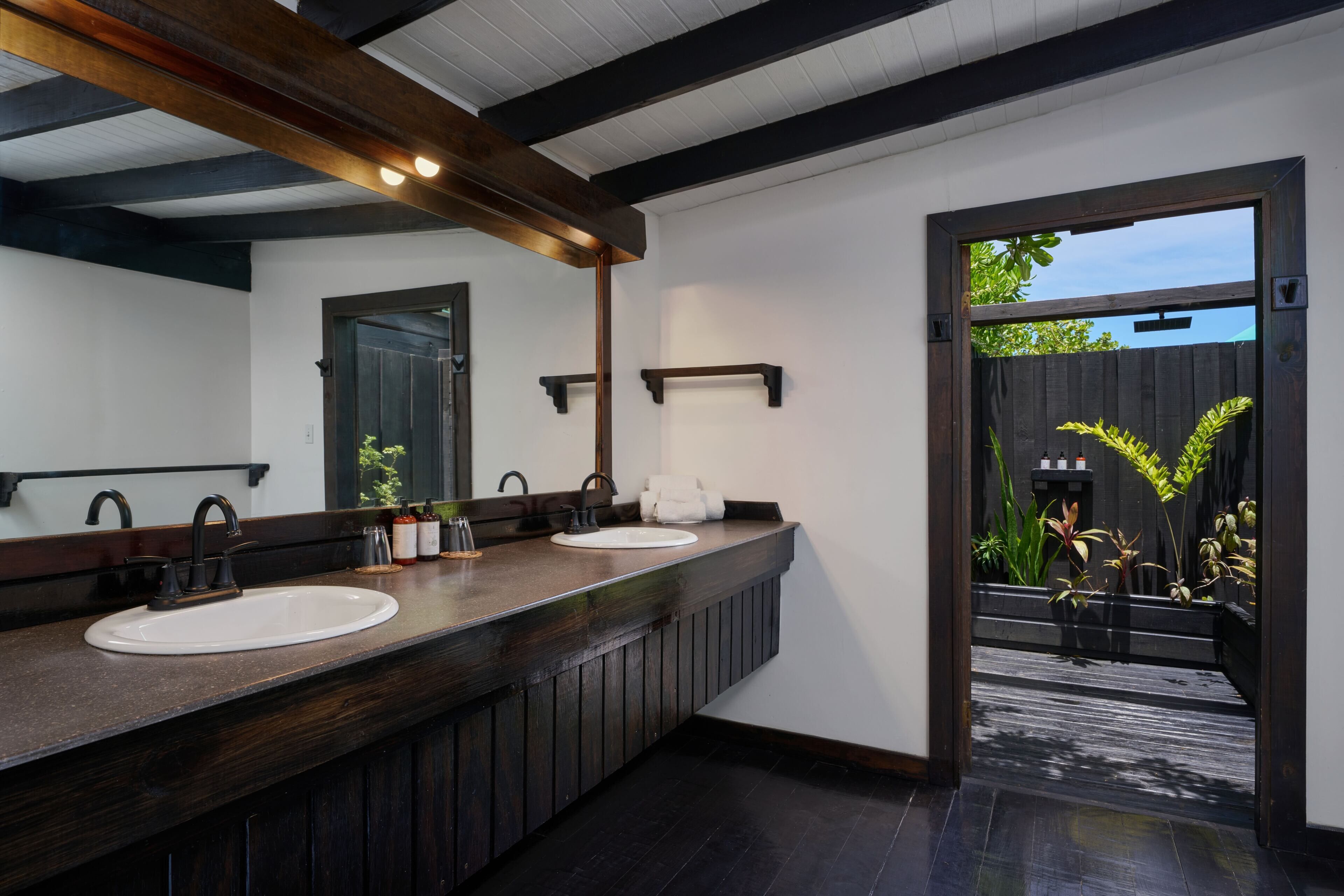 Un baño moderno con tocador de madera oscura, dos lavamanos y un espejo grande.