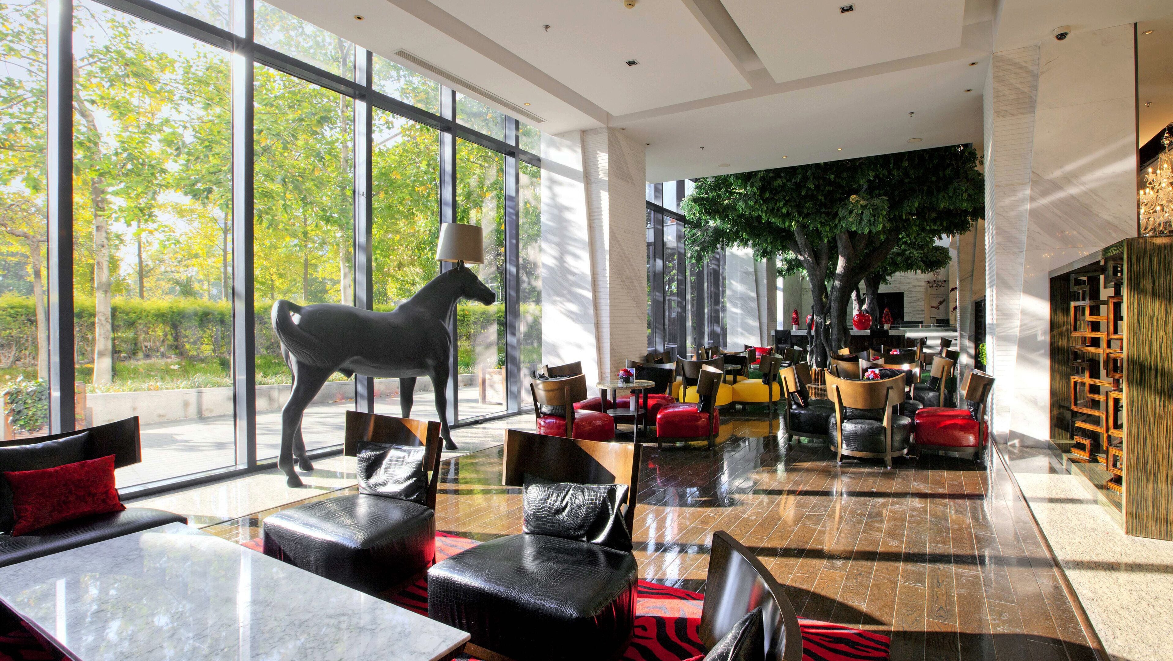 A spacious indoor area with large windows, a sculpture of a horse, and modern seating arrangements.
