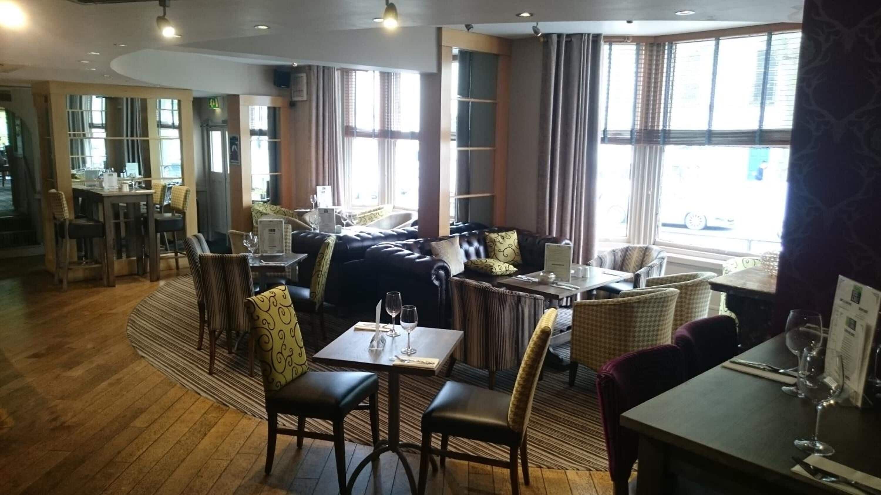 A restaurant with a cozy seating area featuring leather sofas and wooden tables.