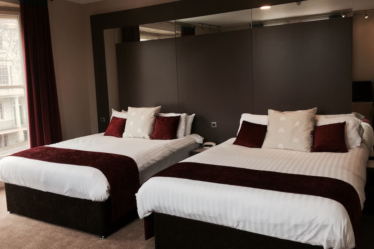 Een hotelkamer met twee bedden, donkere hoofdeinden en een grote spiegel.
