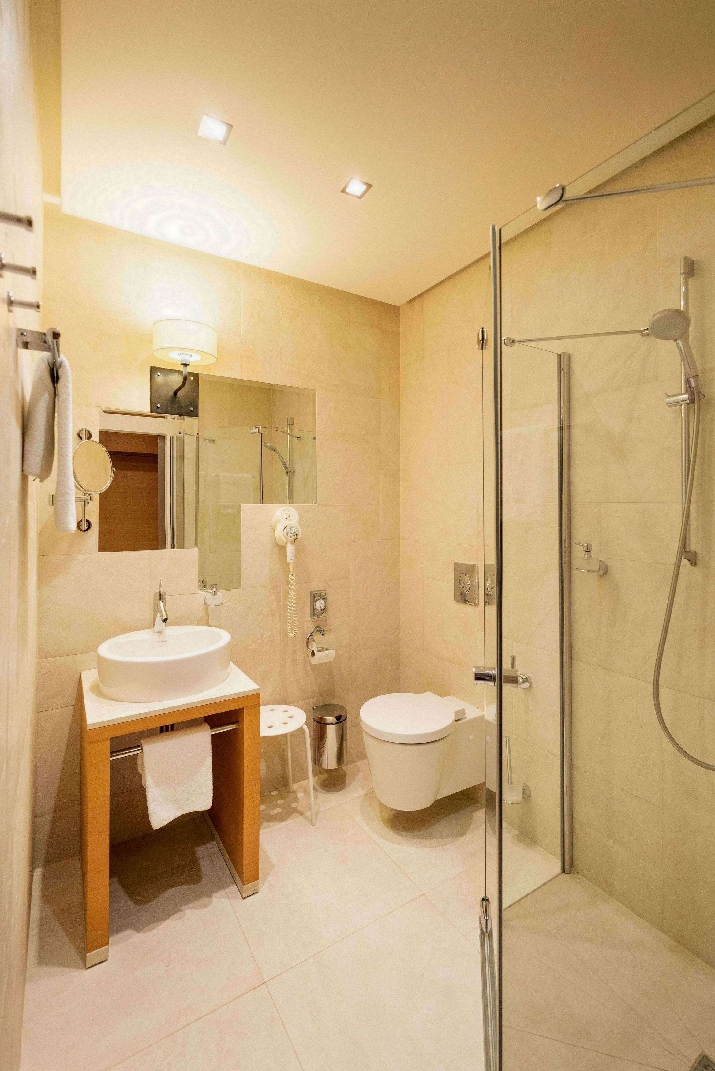 Une salle de bain moderne avec une douche à parois de verre, un meuble-lavabo à deux vasques et des toilettes.
