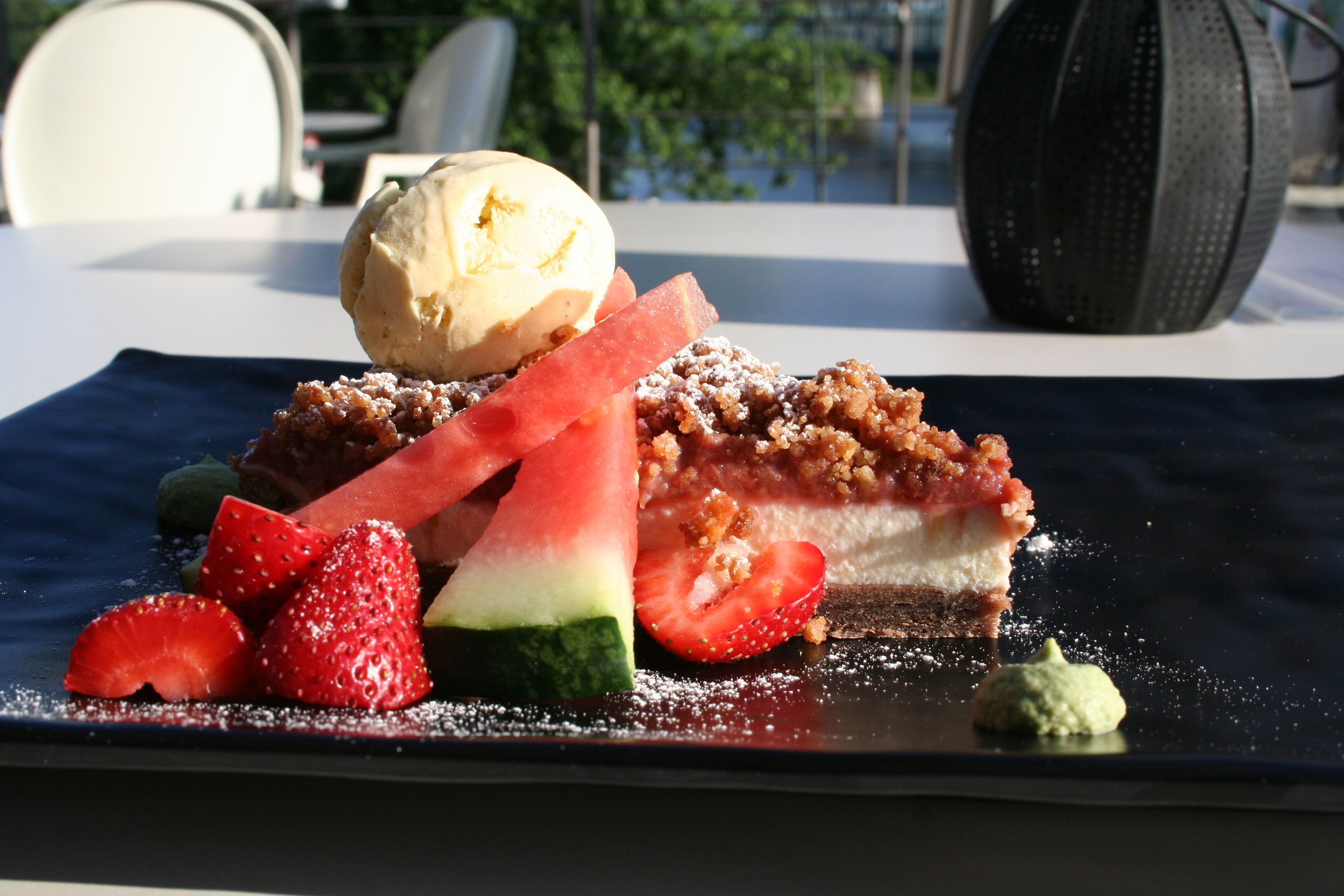 A dessert plate with a slice of pie, strawberries, watermelon, and a scoop of ice cream.