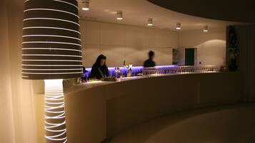 Un área de bar moderna con mostrador curvo, iluminación ambiental y una columna decorativa.