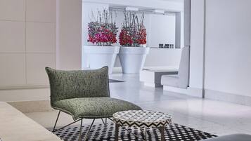 Un moderno hall con un tapete estampado, un sillón verde y un reposapiés blanco y negro.