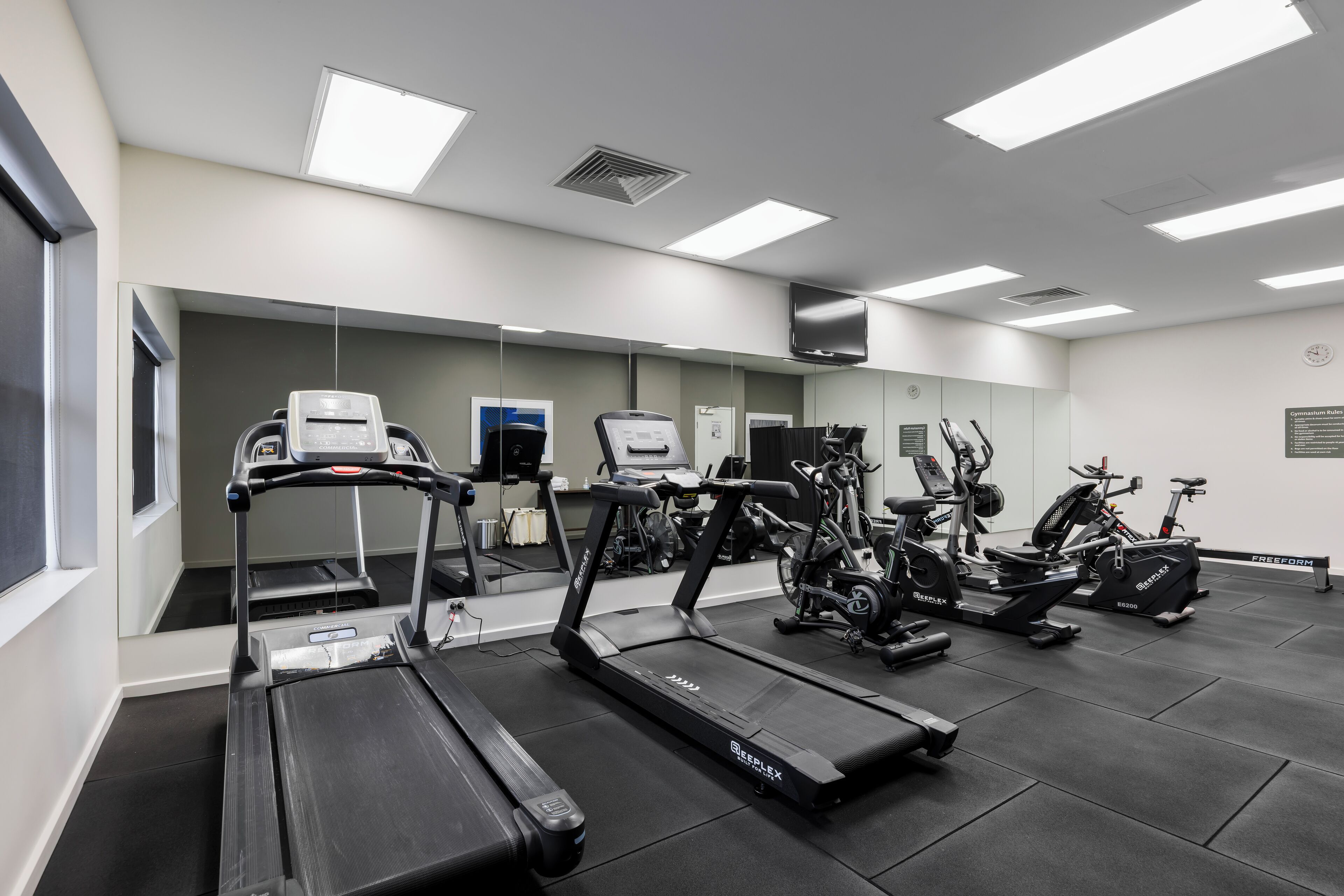 A gym with treadmills, stationary bikes, and exercise equipment.