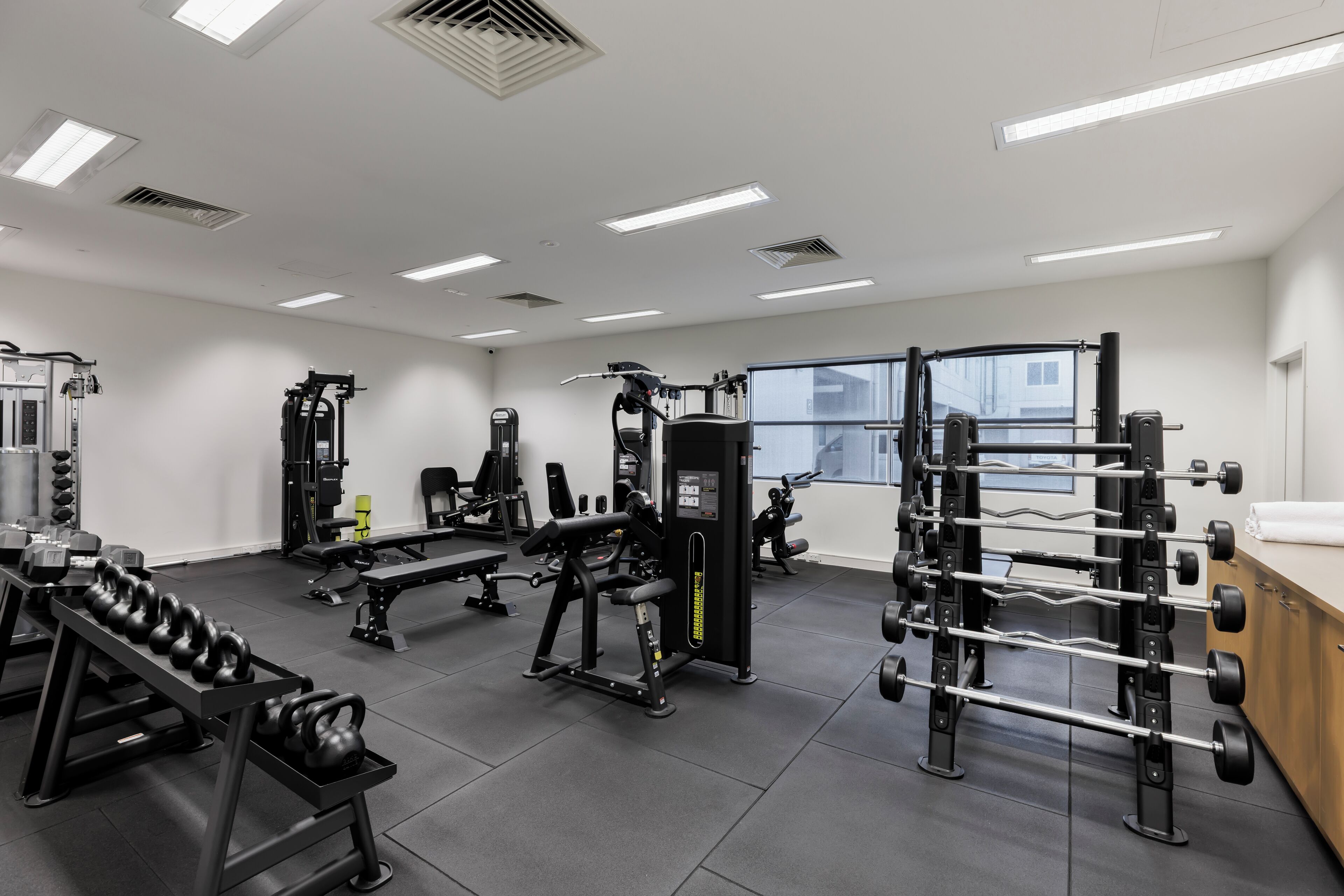 A gym with various exercise equipment, including dumbbells, benches, and weight machines.
