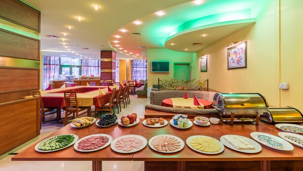 A breakfast buffet with various food items and a seating area with tables and chairs.