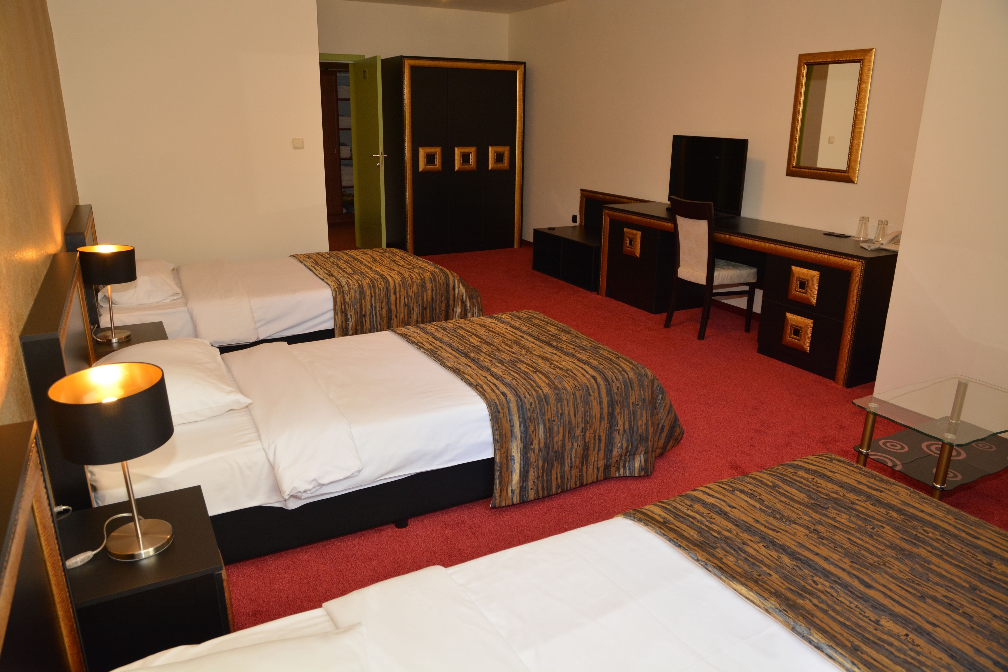 A hotel room with two beds, a desk, a chair, a TV, and a mirror.