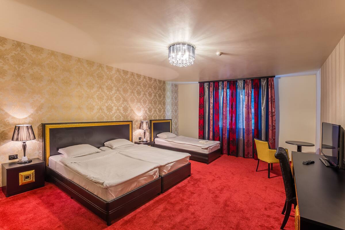 A hotel room with two beds, a TV, a desk, and a chair.